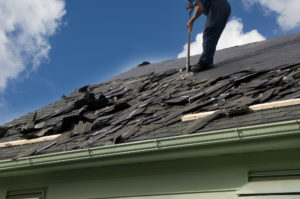 Removing old shingles to prepare a roof for a new installation with blue sky